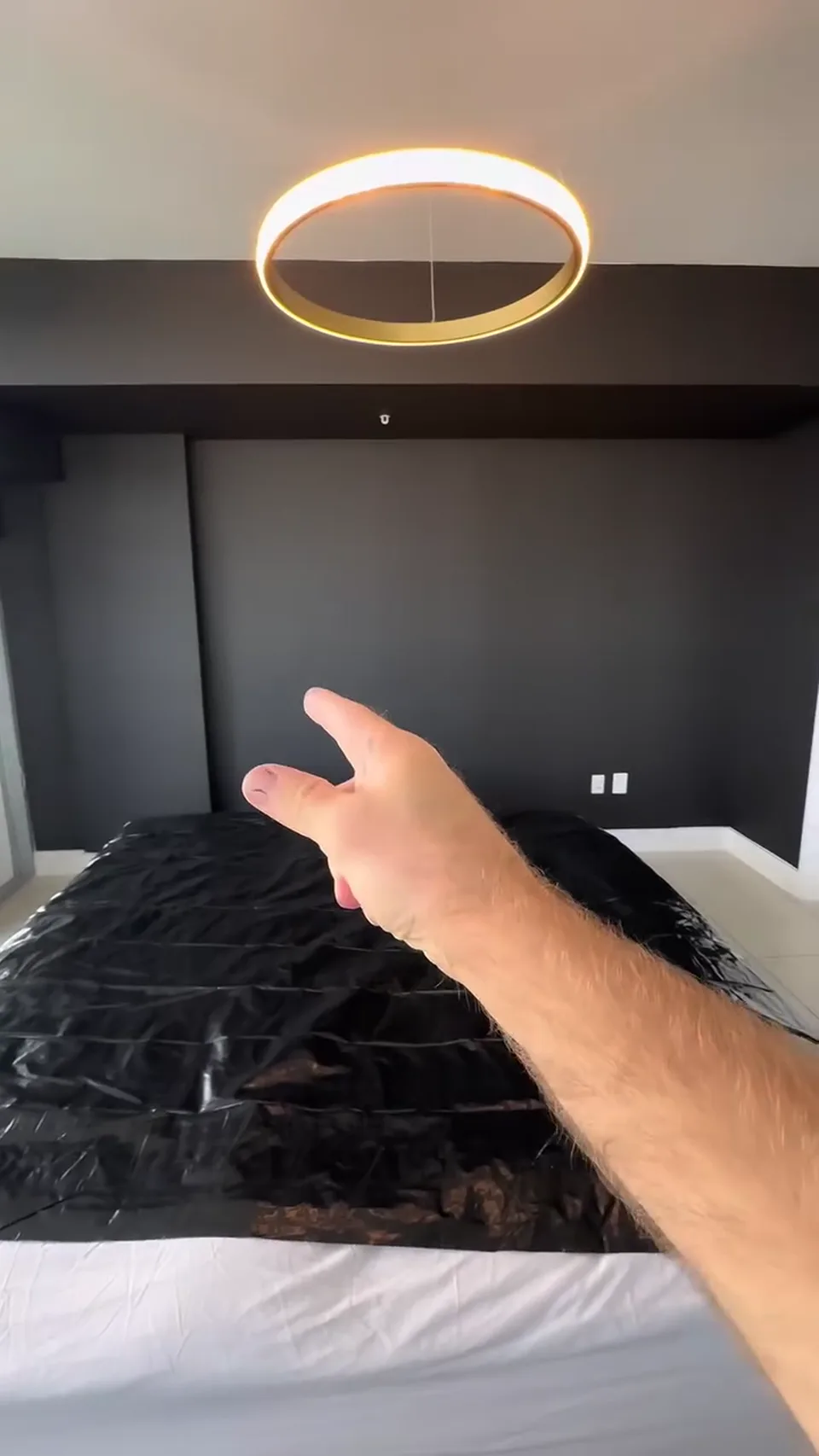 The same bedroom with a black accent wall, white ceiling and covered furniture.