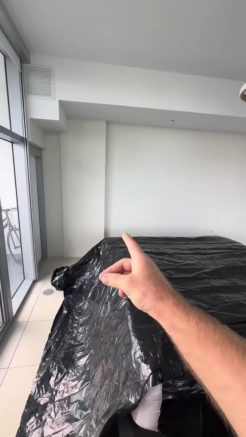 White bedroom wall with furniture covered before painting.